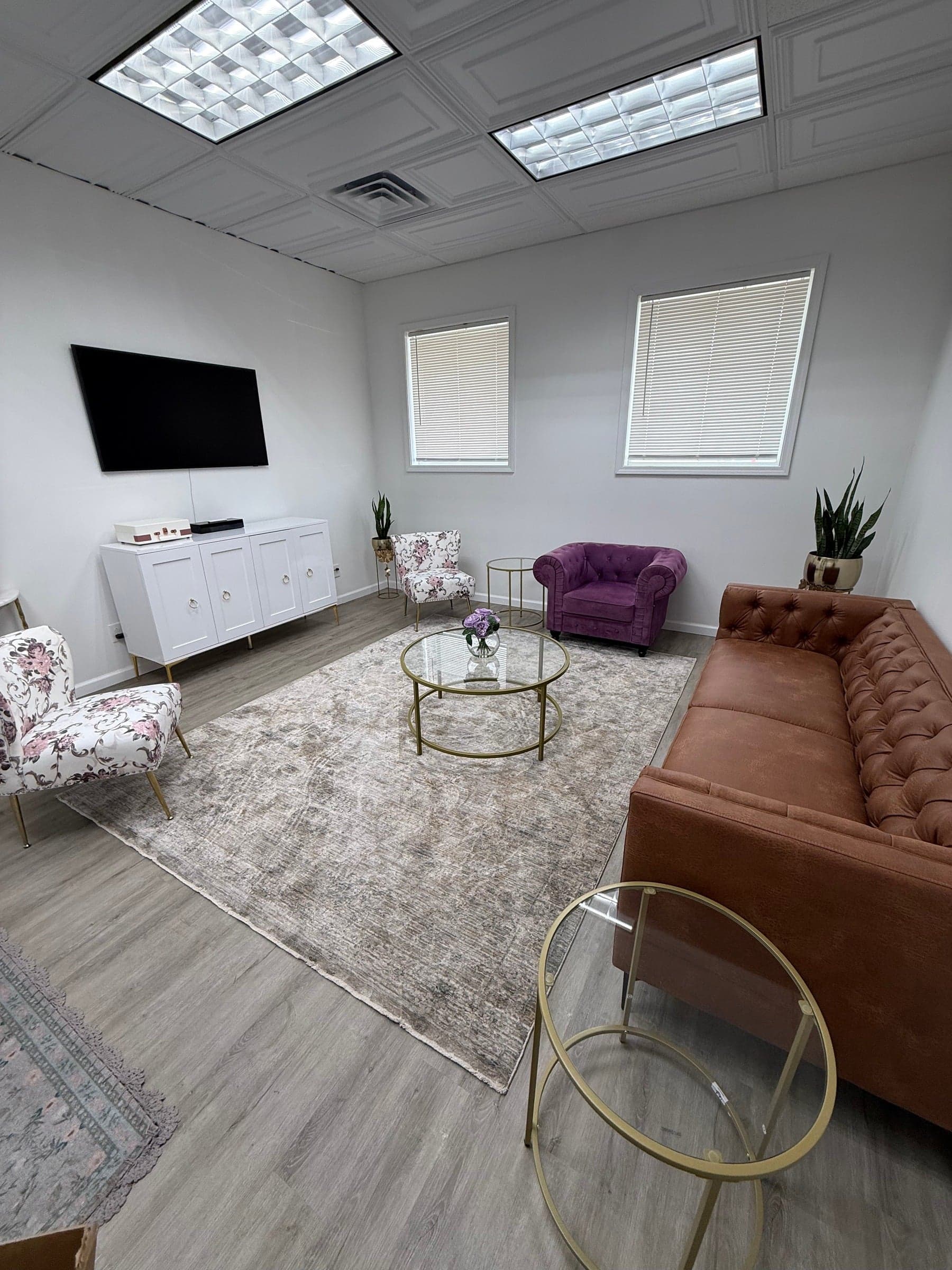 The sitting lounge with a TV, leather sofa, and armchairs
