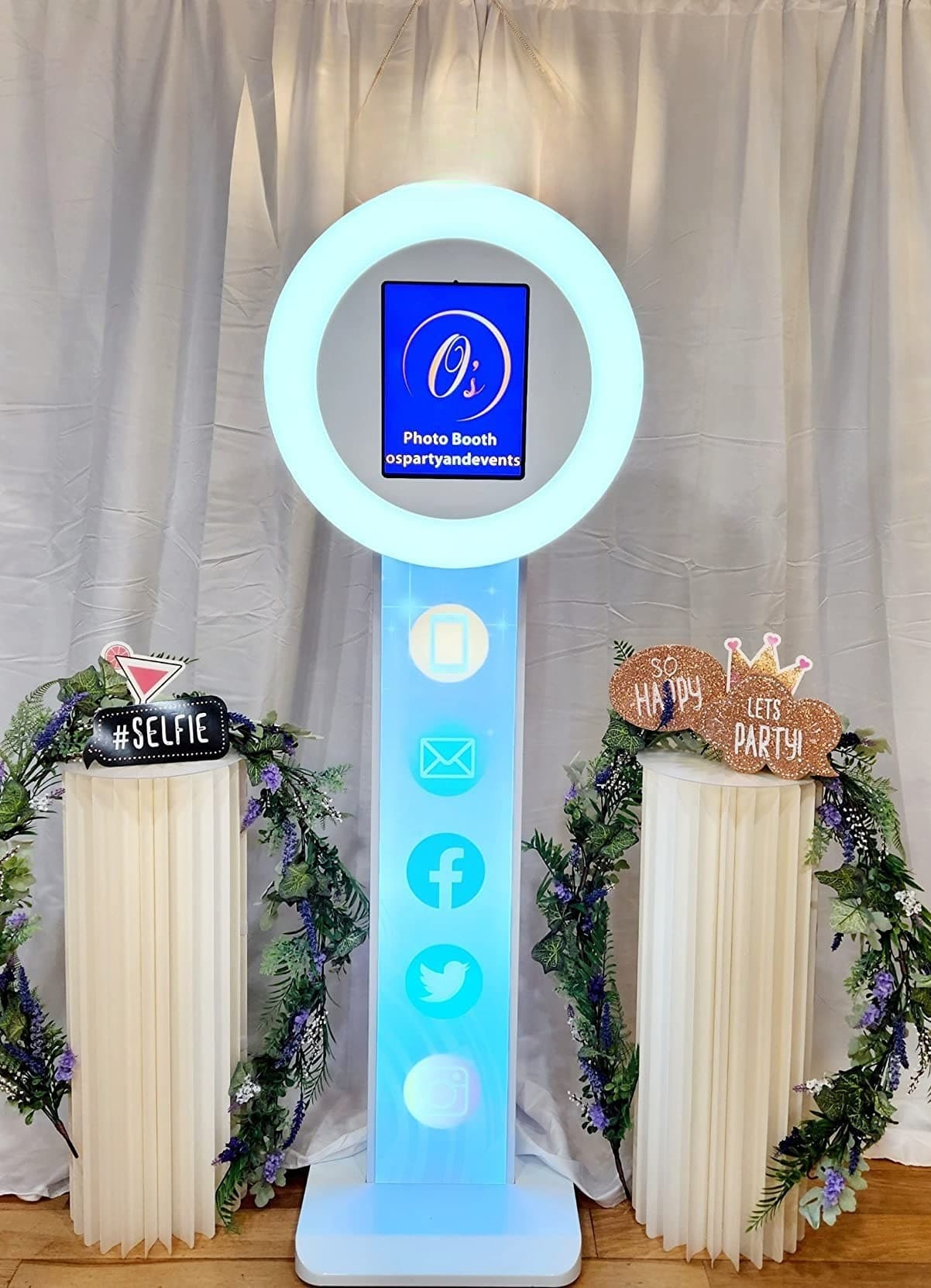 The ring light photo booth flanked by floral pillars
