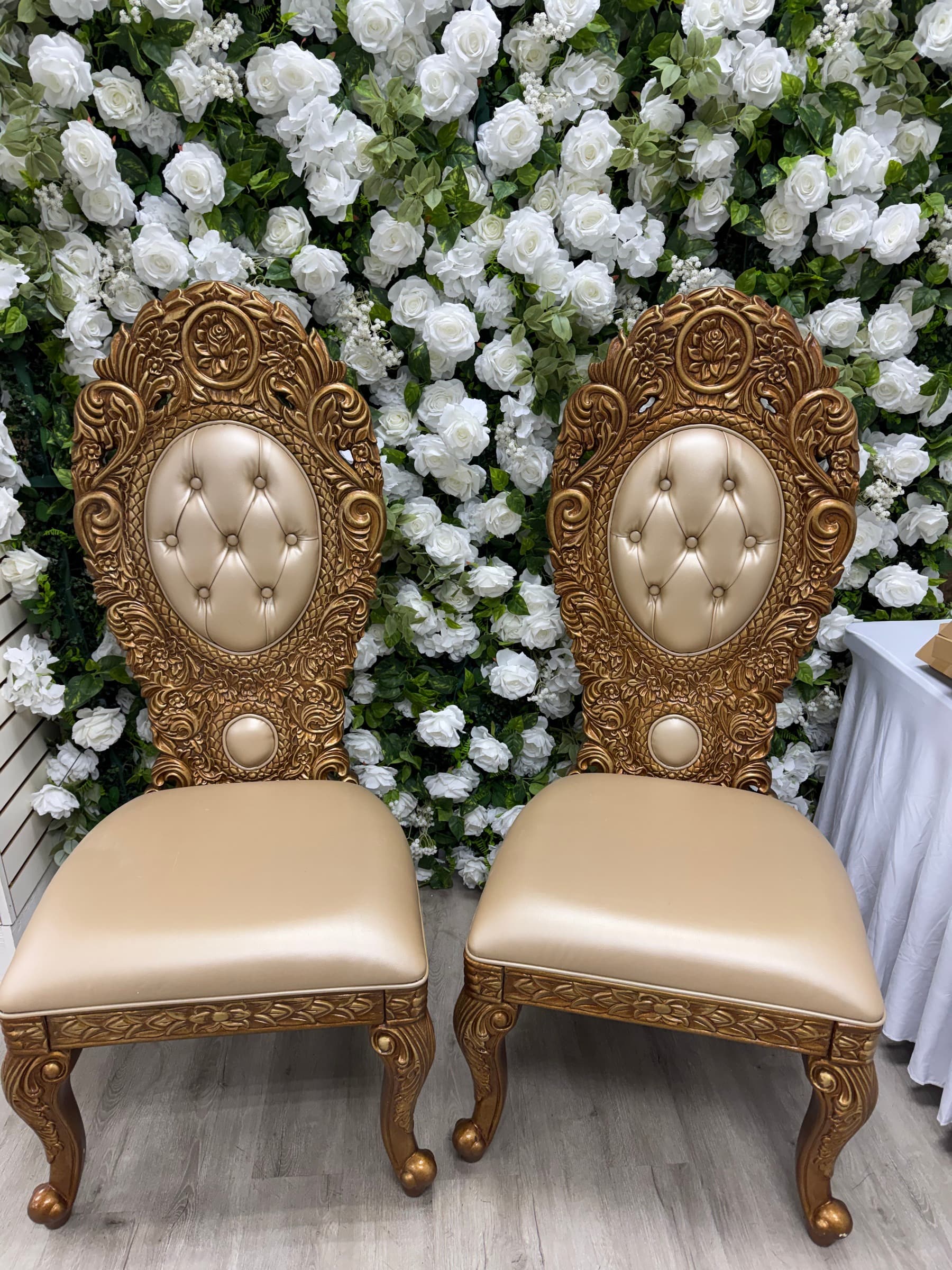 The gold throne chair set in front of the white rose flower wall
